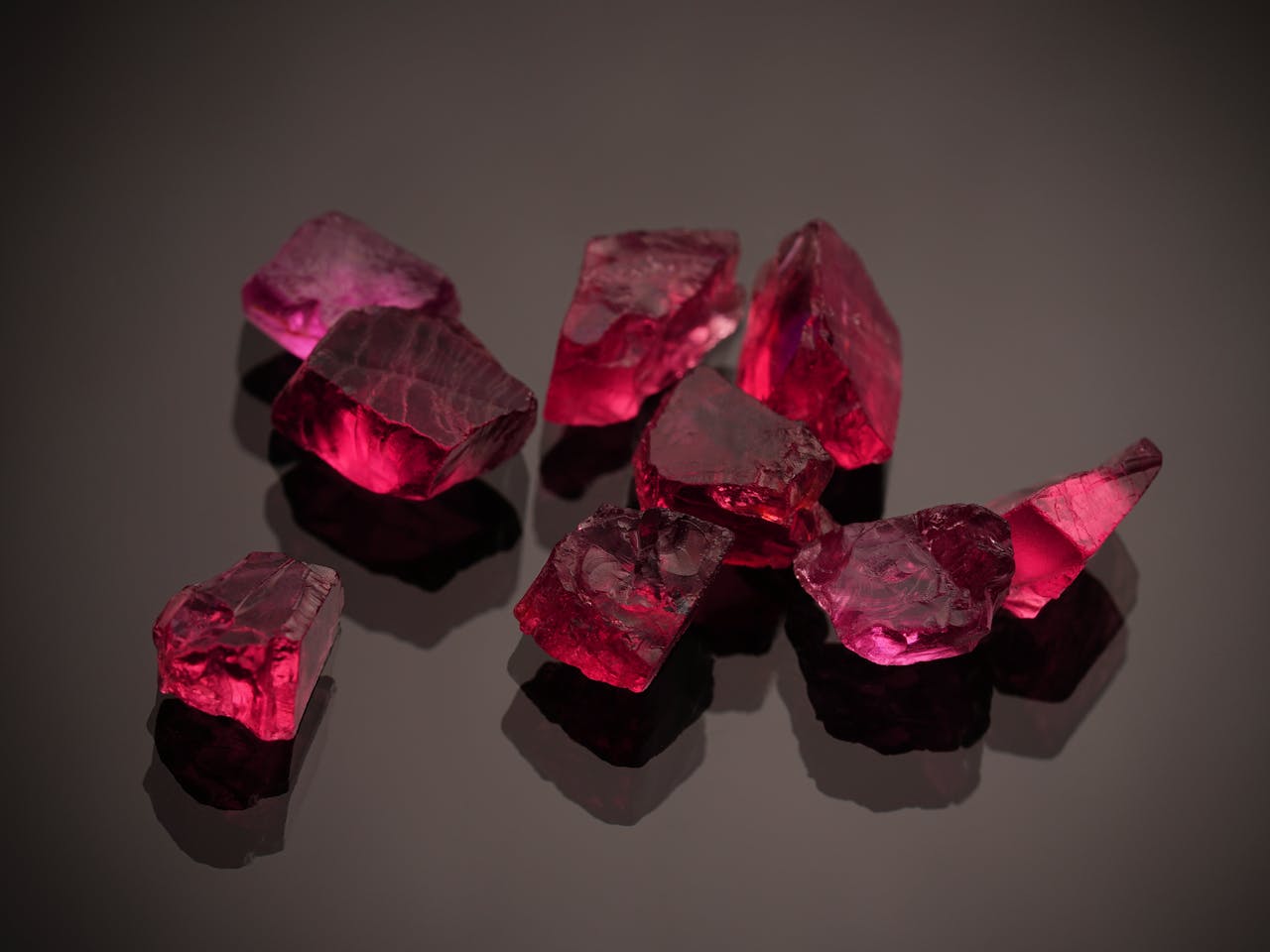 who-we-are Close-up photo of vibrant red gemstones on a shiny black surface, showcasing brilliance.